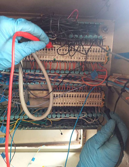 Diagnostic électrique d’une machine industrielle Technicien réalisant des mesures sur les borniers d’une armoire électrique industrielle